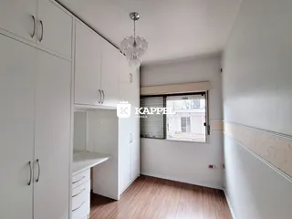 Quarto com armários brancos e piso de madeira clara.