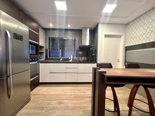 Cozinha moderna com armários brancos e piso de madeira.