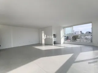 Ambiente interno amplo com piso claro e grande janela de vidro.