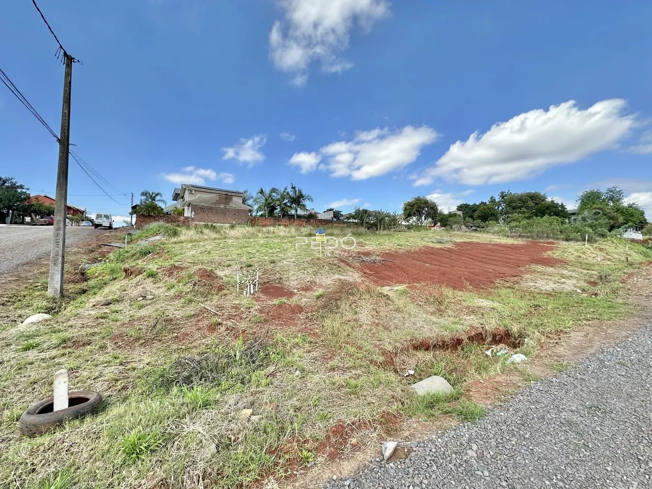 Campo aberto com vegetação seca e terra ao lado de uma estrada rural.