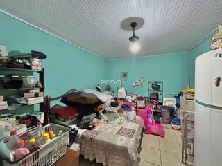 Quarto com bastante desordem e objetos espalhados no chão.