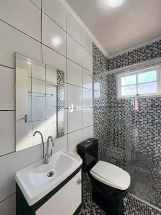 A foto mostra o interior de um banheiro com revestimento de azulejos pretos e brancos.