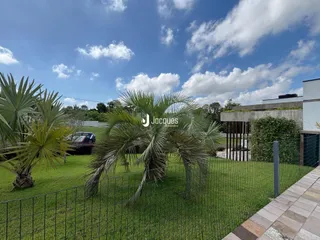 Vista externa da propriedade com jardim e palmeiras.
