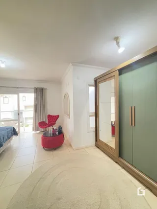 Sala de estar clara com janela e cortinas brancas.