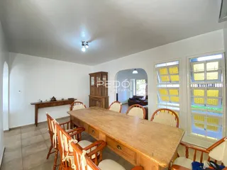Uma sala de jantar com mesa de madeira e cadeiras no interior da residência.