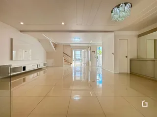 Uma longa área de corredor com piso de cerâmica clara e paredes brancas.