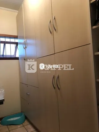 Armário alto de cor clara com portas de vidro instalado na parede.