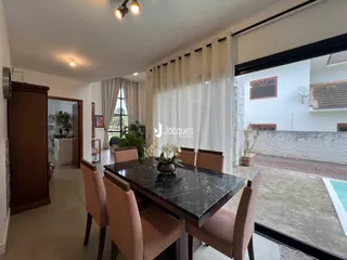 Foto de uma sala de jantar com mesa de mármore escura e grandes janelões.