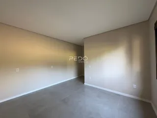 Vista interna de um cômodo com paredes claras e piso de grande formato.
