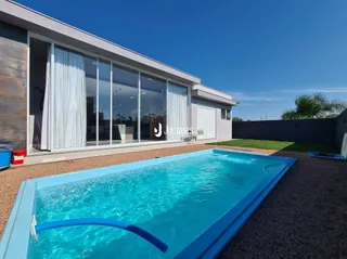 Piscina azul em frente à fachada de uma casa moderna.