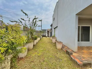 Vista da fachada de uma residência com jardim lateral.