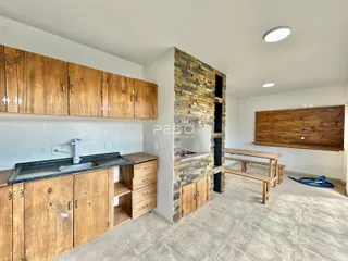 Interior de uma cozinha com armários de madeira e parede de pedra em Lajeado.