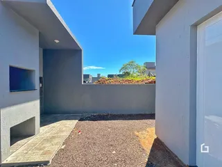Vista externa do quintal com piso de cascalho e vegetação ao fundo.