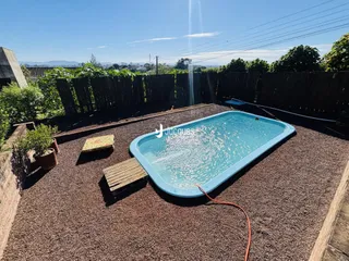 Vista externa de uma piscina em uma área de jardim com cerca de madeira.