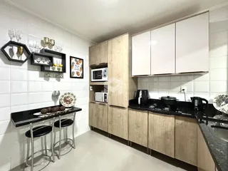 Cozinha com armários de madeira e revestimento branco.