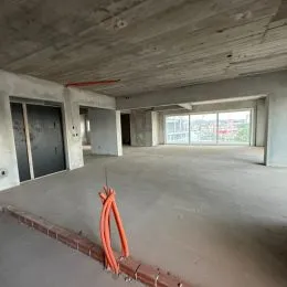 Foto de um espaço interno amplo e em construção com teto de concreto aparente.
