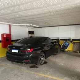 Foto de um carro preto estacionado em uma área externa.