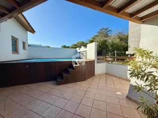 Vista da área externa com piscina e parede branca.