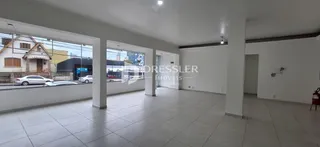 Interior de uma sala ampla com piso de cerâmica e grandes janelas.