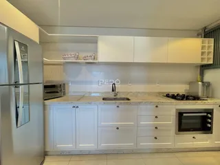 Cozinha moderna com armários brancos e bancadas claras.