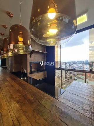 Interior de uma sala com um lustre de vidro grande sobre piso de madeira.