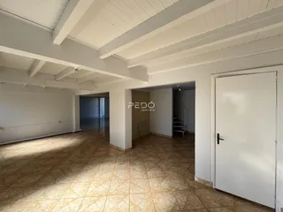 Interior de uma sala com piso de cerâmica e forro de madeira branca.