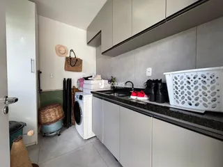Vista interna de uma cozinha com armários brancos e bancada escura.