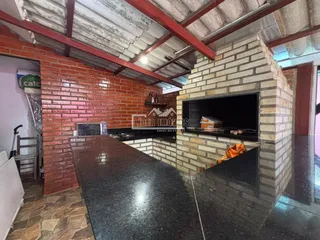 Interior de uma cozinha com paredes de tijolo aparente e teto de vigas.