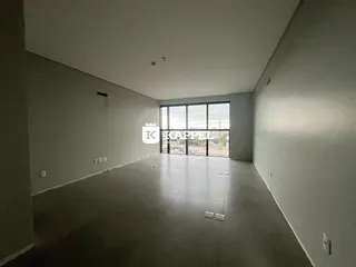 Sala ampla com piso claro e grandes janelas voltadas para o exterior.