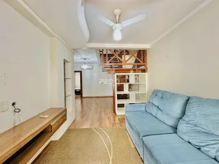Sala de estar com sofá azul e piso de madeira clara.