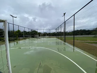 Foto de uma quadra esportiva externa com linhas pintadas e cerca de tela.