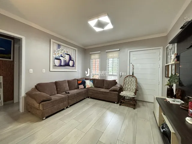 Sala de estar com sofá marrom e piso de madeira clara.