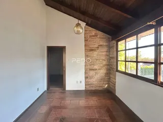 Interior de uma sala com piso de madeira e parede de pedra em uma residência.