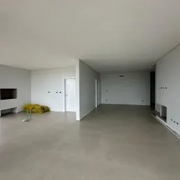 Foto de um ambiente interno amplo e vazio com paredes brancas.