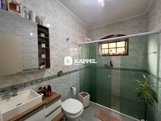 Banheiro com revestimento de azulejos claros e bancada branca.