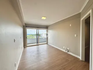 Ambiente interno de uma sala com piso de madeira clara e grandes portas de vidro.