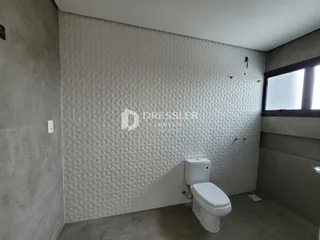 Ambiente interno de um banheiro com parede texturizada e piso de concreto.