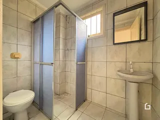 Foto de um banheiro com revestimento cerâmico e box de vidro.