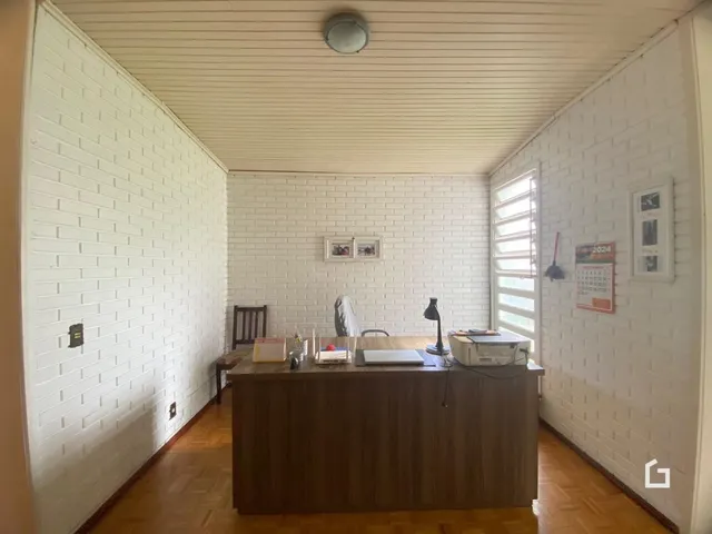 Interior de uma sala com paredes de tijolo branco e piso de madeira.