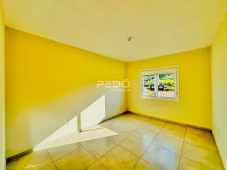 Sala de estar com paredes amarelas e piso de cerâmica.