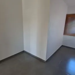 Vista de um corredor interno com paredes brancas e piso escuro.