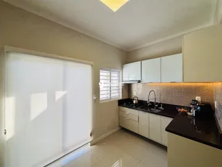 Foto de uma cozinha com armários brancos e bancadas escuras.