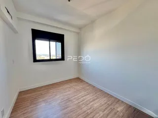 Ambiente interno com piso de madeira clara e janela.