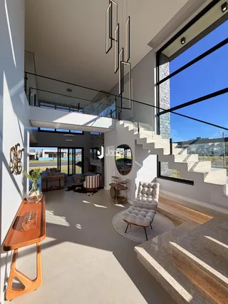 Vista de um ambiente interno moderno com escadaria e grandes janelas.