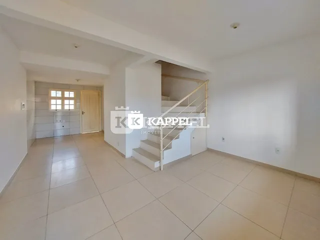 Hall de entrada com escada e piso claro em um imóvel.