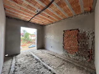 Interior de uma sala com parede de tijolos expostos e piso de terra