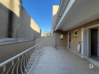 A foto mostra a fachada de um prédio com uma área externa pavimentada.