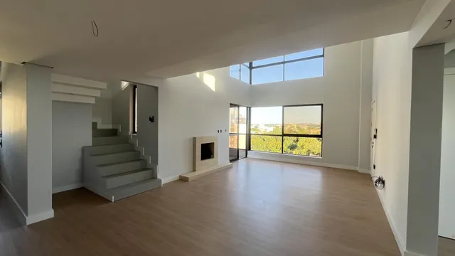 Sala de estar ampla com piso de madeira e vista panorâmica para a cidade.