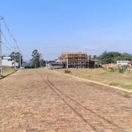 Vista de um terreno aberto com solo de terra vermelha e vegetação seca.