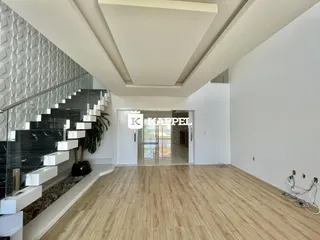 Sala de estar ampla com piso de madeira e escadaria moderna em um imóvel.